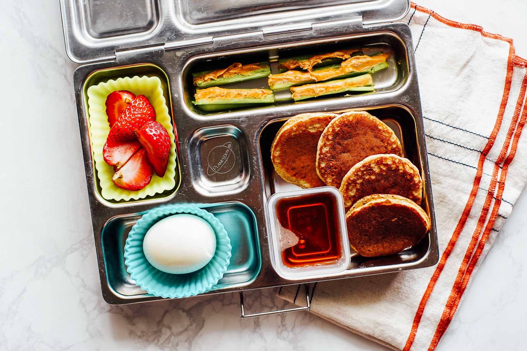 Pancakes for lunch with maple syrup, hardboiled egg, celery with peanut butter, and strawberries.