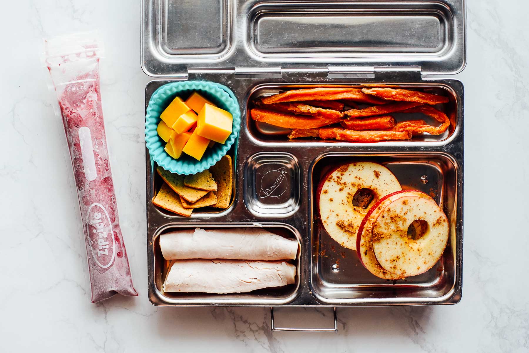 Apple slices sprinkled with cinnamon, turkey rolled up, carrot fries, cheese cubes, crackers.