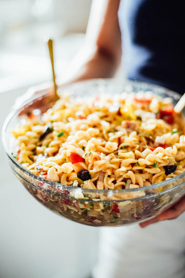 Holding a large glass bowl of pasta salad.